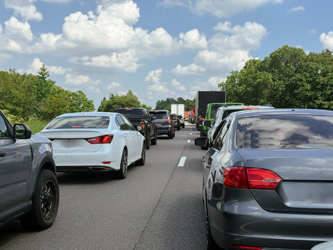 Rows of passenger cars stand closely together on a crowded highway during daytime travel. The image shows commuting conditions, transportation pressure, and real road congestion.