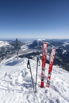 Ski stuck in snow, Alpspitz summit with summit cross, ski tour to Alpspitze, view to Garmisch-Patenkirchen, Wetterstein mountains with snow in winter, Garmisch-Partenkirchen, Bavaria, Germany