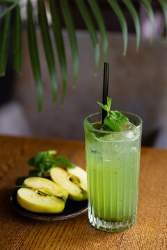 Refreshing drink with mint and apple slices on wooden table in cafe during afternoon setting