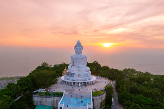 A magnificent white marble Buddha statue sits serenely atop a lush Phuket hilltop