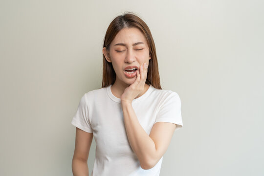 Face expression suffering from sensitive teeth, Asian young woman touching cheek