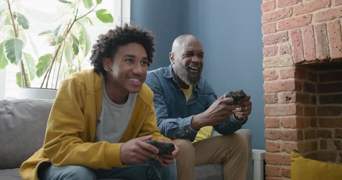 Father and Son Enjoying a Video Game Together at Home on Sofa