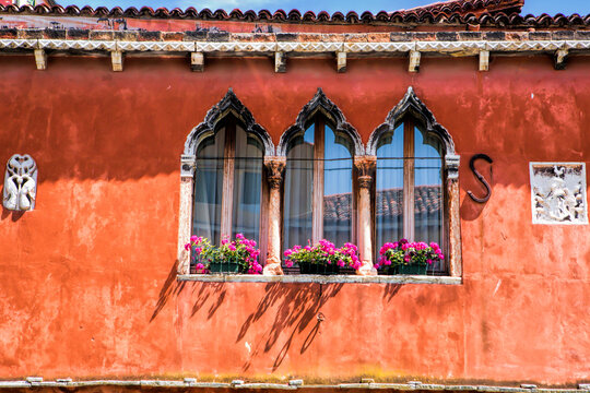 Close-up of a historic red house facade in Venice with Gothic arched windows