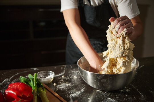 Woman kneading fresh dough in bowl during cooking process