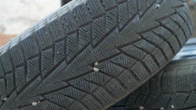 Stack of dark rubber tires with visible grooves. Autumn requires switch from summer to winter tires for safety on cold road. Special tread ensures stability. Early replacement prevents accident