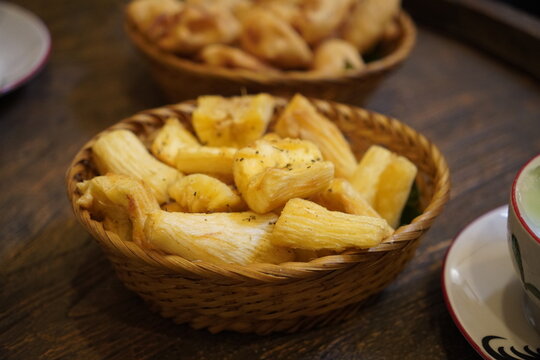 Fried cassava served in woven basket on rustic wooden table