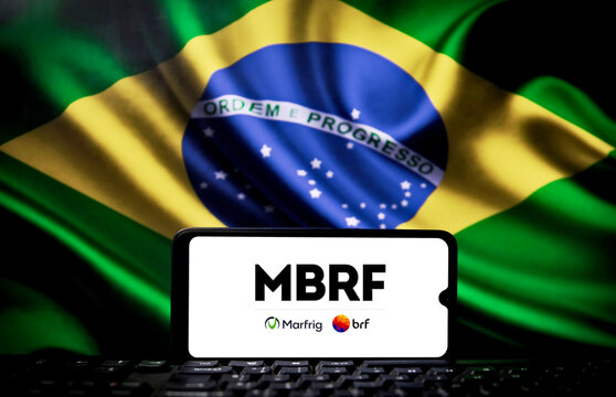 MBRF logo on a smartphone screen with the Brazilian flag in the background. Brazilian company MBRF and Saudi Arabian company Salic expand food security agreement.