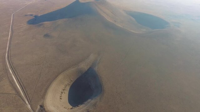 Aerial view of volcanic tuff ring cone crater and a barren geological sinkhole depression formation. Rocky terrain, arid caldera, topography, wilderness depict rugged regional geology natural history.
