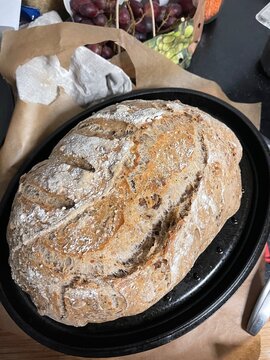 Close-up of a crusty loaf of artisanal bread in a black oval dish. Perfect for food, baki
