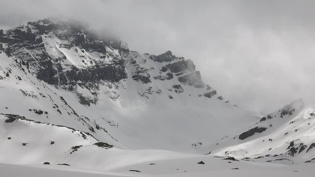 Small natural avalanche falling down a rocky mountain slope after severe damage in stark aftermath. Winter mountains, alpine terrain, wilderness, and unmanned depict crisis evidence and destructive.
