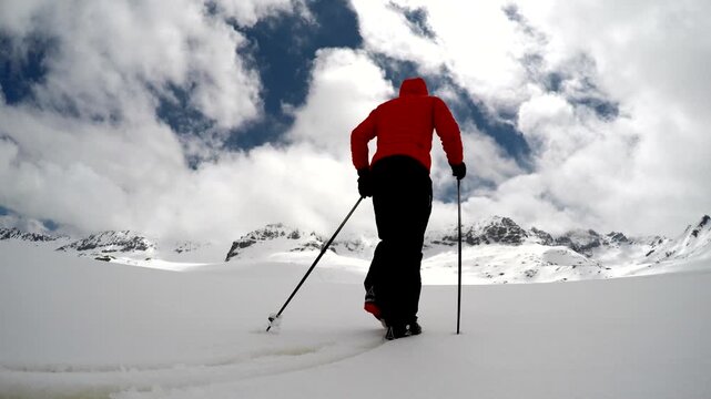 Man in red coat hiking across snowy Antarctic mountains under bright winter clouds. Antarctica, surrounded, aviation, and glacier suggest adventure leisure and freeflight energy.