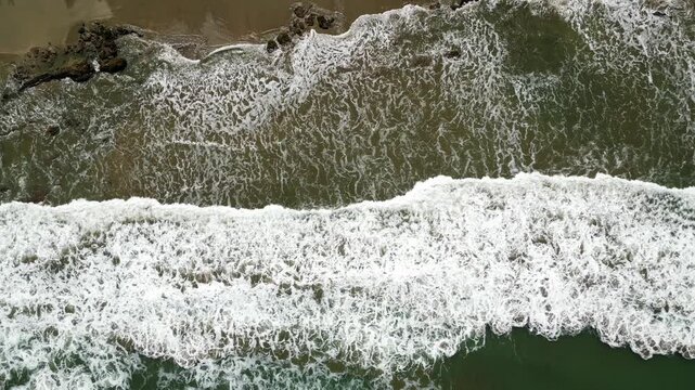 Drone shot of a horse running on the beach towards a group of people, Mancora, Peru