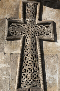 Ornate khachkar carved on a stone wall, symbolizing armenian christian tradition with intricate knotwork patterns and historical significance at noravank monastery complex