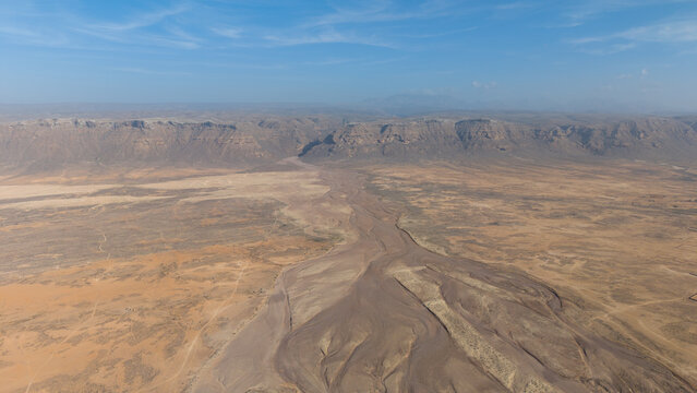Aerial Desert Valley with Dry Riverbed and Mesa Cliffs