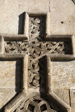 Intricate details of a traditional armenian khachkar cross stone, displaying elaborate ancient religious stone carving and decorative ornament on a weathered monastery wall in sunlight