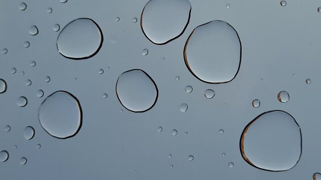 Drops of water or acid on a blue background, close-up