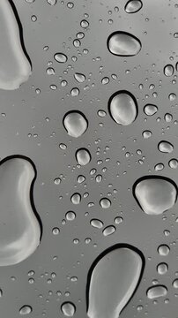Raindrops or acid dripping onto glass from above, close-up
