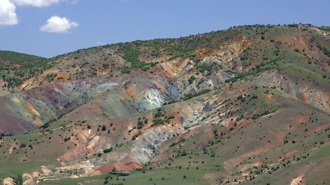 Mineral rich ore bearing mountain slope displays vivid oxidation colors and exposed deposits. Rugged terrain, rocky landscape, alteration, industrial depict rugged regional geology natural.