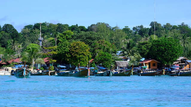 KOH LIPE, THAILAND - 2022: Traditional longtail boats moored along the turquoise coastline of Koh Lipe island, a popular tourist destination in Satun province.