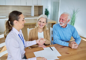 Obraz premium Happy senior old family couple clients make financial insurance estate business deal contract signing and shaking hands, agent lawyer, satisfied mature customers signing contract meeting bank manager 