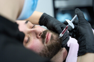 Fototapeta premium Man receiving dermal filler injection for skin rejuvenation