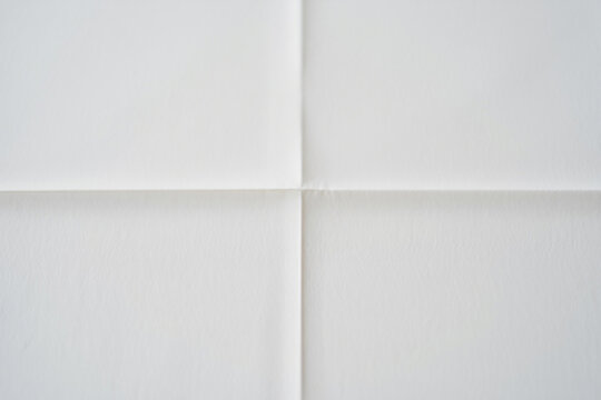 Abstract background of white paper folded in four creating intersecting lines and soft shadows