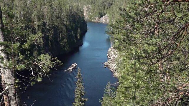A motorboat is crusing along the canyon lake Julma-&Ouml;lkky, Finland, on a sunny day 