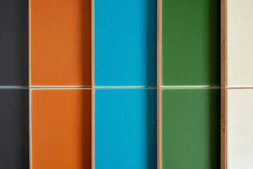 Fototapeta premium Close-up of colorful glazed ceramic tiles arranged in grid, vibrant orange, bright blue, deep green and neutral beige squares, textured grout lines, contemporary design