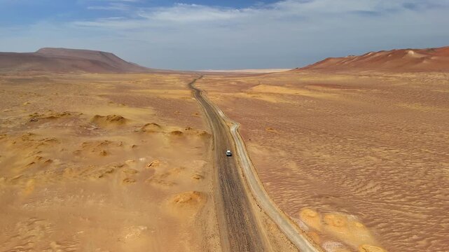 Aerial drone view of a car driving in Paracas. The Pacific Ocean and cliffs of Paracas. Dramatic Pacific landscape. Panoramic coastal view. Peru, Ica Region.	