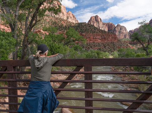 woman from behing leaning on a railing looking at the Virgin River in Zion National Park