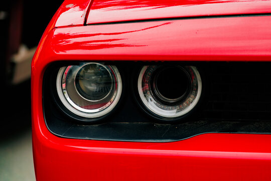 Close up of red sports car headlights with modern design, automotive detail with dual circular lamps, glossy body surface and aggressive styling concept