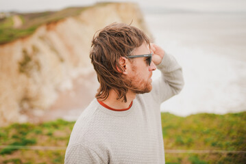 Man stands by cliffside, hand shielding eyes © Reuben