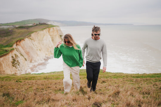 Couple walks hand-in-hand along cliffside path
