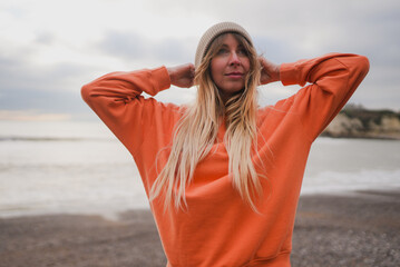 Woman stands on beach, hands behind head © Reuben