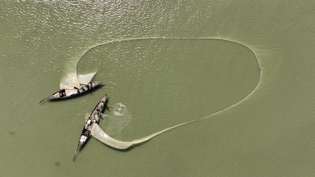 Two fishermen in Bogra orchestrate a perfect circle of life, casting their nets across the emerald ripples of the river.