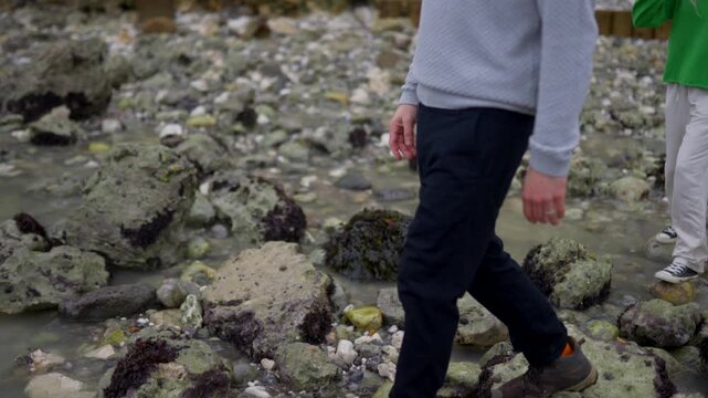 Man carefully steps across a rocky tidal pool during low tide