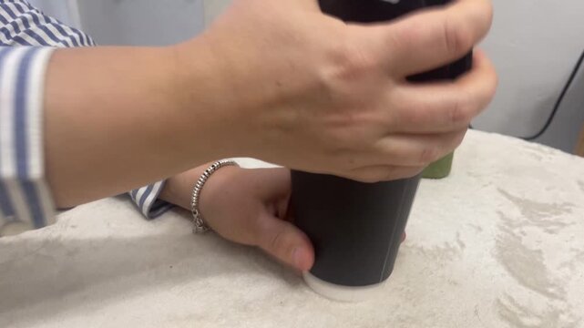 The plastic lid is removed from the paper cup with a popping sound