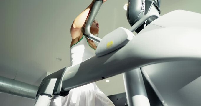 Woman Exercising on Elliptical Machine at Gym