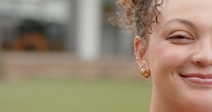 African American woman hearing off-camera voice, shifting smile into laugh on lawn with gold hoops