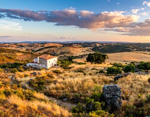 Fototapeta premium A sun-kissed, picturesque landscape with a rustic building nestled amidst rolling hills and a vibrant, colorful sky