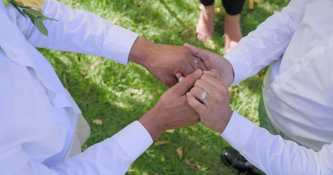 Vertical video: African American men in whites placing rings as minister reading tablet in park