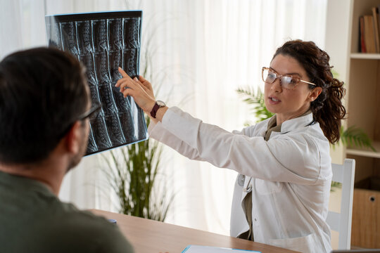 Woman doctor discussing lumbar spine MRI scan findings with patient during consultation