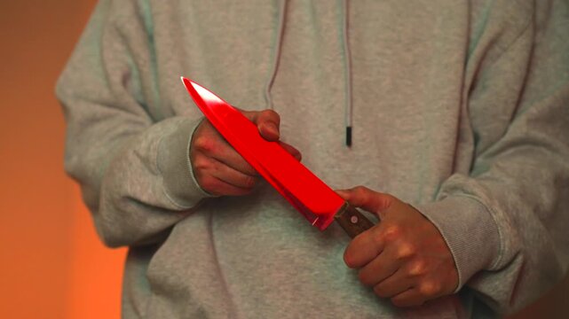 A close-up of a man's hands holding a sharp kitchen knife.
Assault or domestic violence.
An aggressive man brandishes the blade of a knife at his victim.