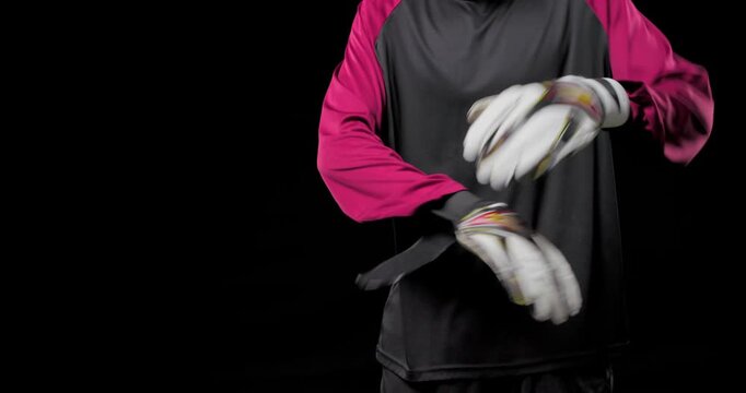 Vertical video: African American male goalie adjusting white gloves, preparing for play on turf
