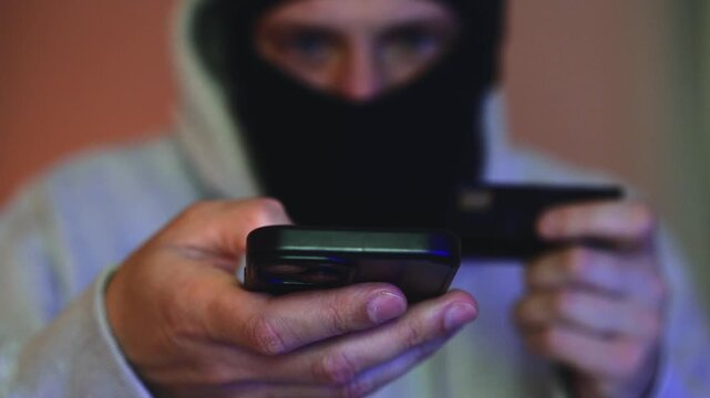 A criminal hacks someone else's bank account using a mobile phone to steal money, financial fraud, theft of someone else's finances, the light from police flashing lights