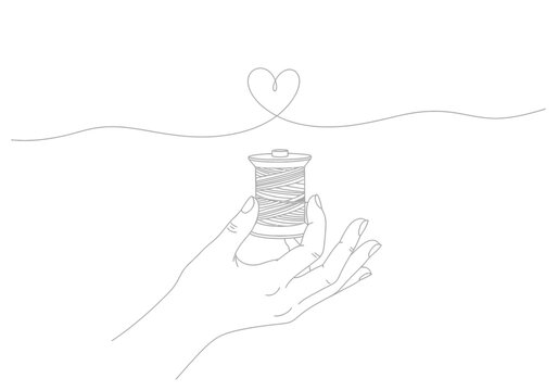 Hand holding a spool of thread with a continuous line forming a heart shape