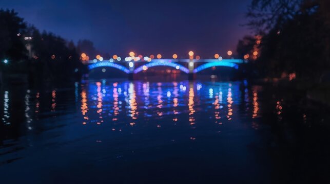 Blue illuminated bridge spanning across a calm river at night with colorful lights reflecting on the water surface slowly