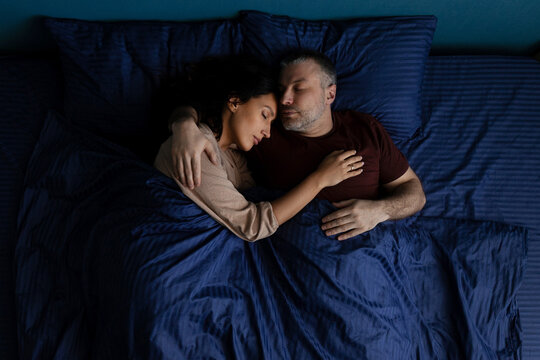 Loving couple sleeping closely in bed, woman resting peacefully on mans chest
