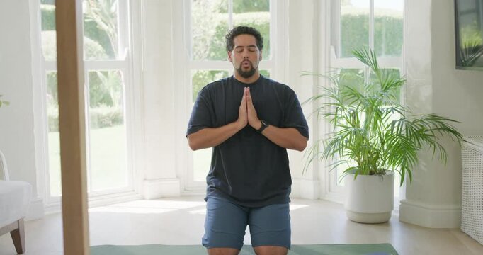 African American man kneeling on mat at bay window in gear, sun urging calm breathing, stretching