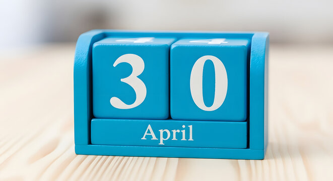 April 30th Date on Blue Calendar Block on Wooden Desk Background